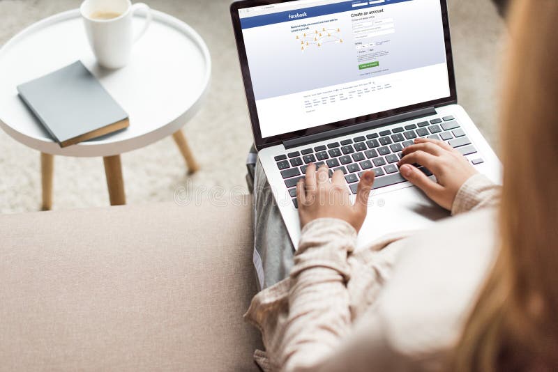 Cropped shot of woman at home sitting on couch and using laptop with facebook