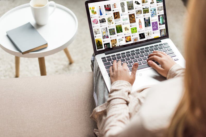 cropped shot of woman at home sitting on couch and using laptop with pinterest website on screen