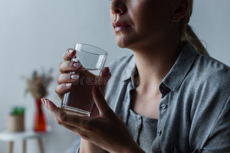 cropped view of sad woman with climax holding glass of water,stock image