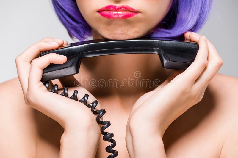 Cropped view of upset girl in purple wig holding retro telephone