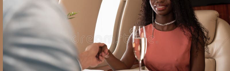 Cropped view of young interracial couple holding hands in private plane