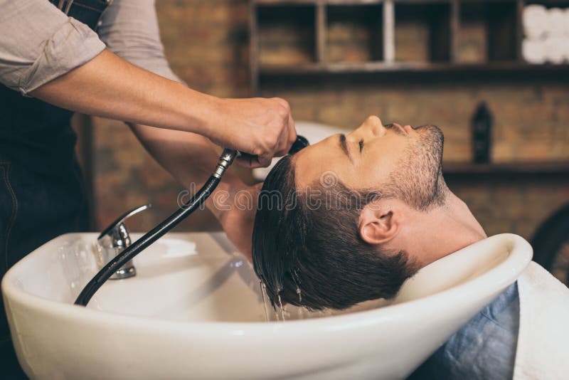 Cropped widoku hairstylist płuczkowi klienci włosiani w fryzjerze męskim obraz stock Cropped widoku hairstylist płuczkowi klienci włosiani w fryzjerze męskim obraz stock