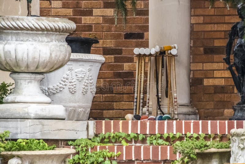 Croquet set leaning against a pillar among flower pots and statuary and plants on the porch of an upscale home - close-up stock images Croquet set leaning against a pillar among flower pots and statuary and plants on the porch of an upscale home - close-up stock images