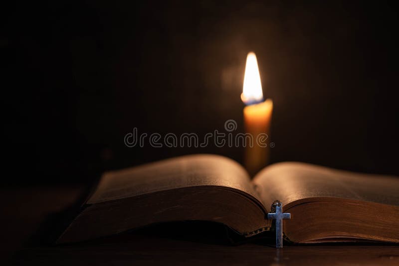 Cross with bible and candle on a old oak wooden table. Beautiful gold background. Religion concept