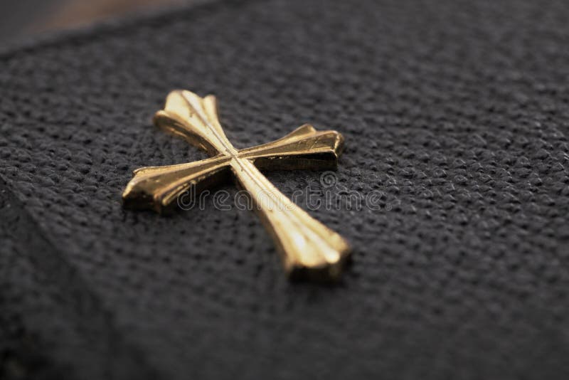 Gold color cross on the cover of an old pocket-sized bible.