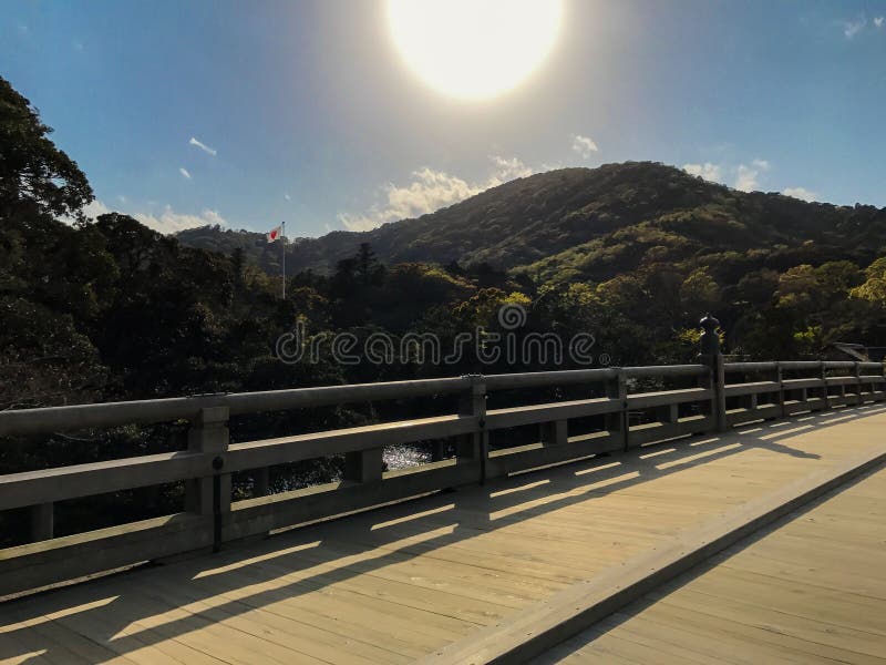 A serene view of a traditional wooden bridge basking in the warm glow of the sun with forested mountains in the background, capturing a peaceful morning in Japan. Capturing sunlight stock images, royalty-free photos and pictures