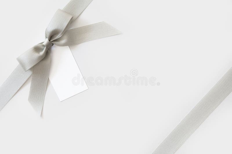 Silver ribbon with a bow as a gift on a white and shiny background stock photos Silver ribbon with a bow as a gift on a white and shiny background stock photos