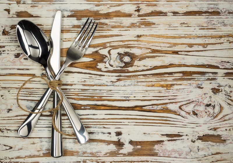 Crossed fork table knife and spoon on old wooden boards royalty free stock photography Crossed fork table knife and spoon on old wooden boards royalty free stock photography
