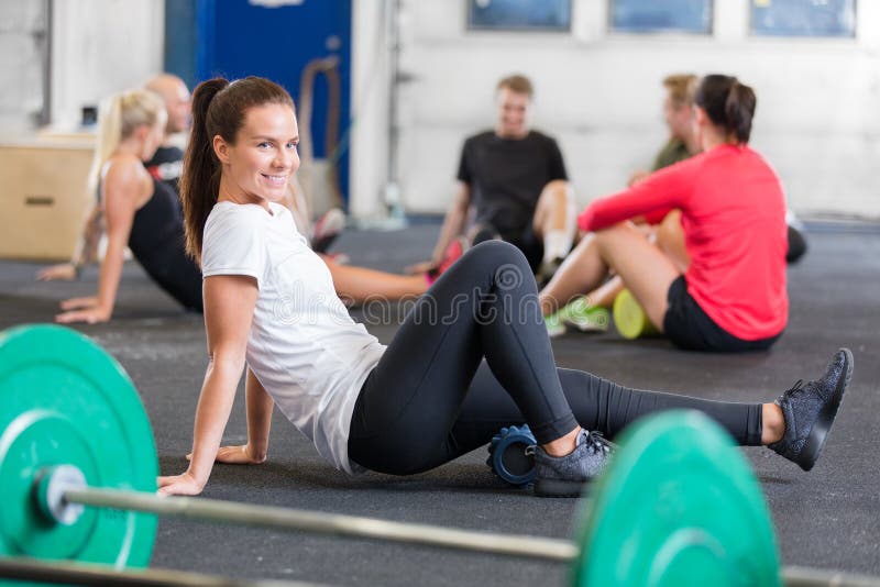 Usmívající se ženy dělají crossfit cvičení pro flexibilitu a mobilitu pomocí jógy, fitness pěnové válce.