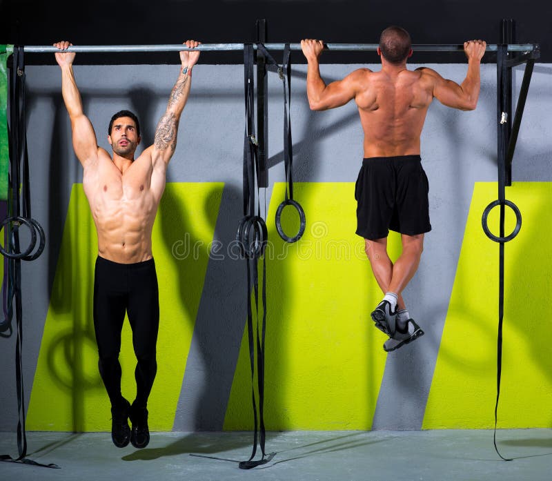 Crossfit toes to bar men pull-ups 2 bars workout exercise at gym. Crossfit toes to bar men pull-ups 2 bars workout exercise at gym