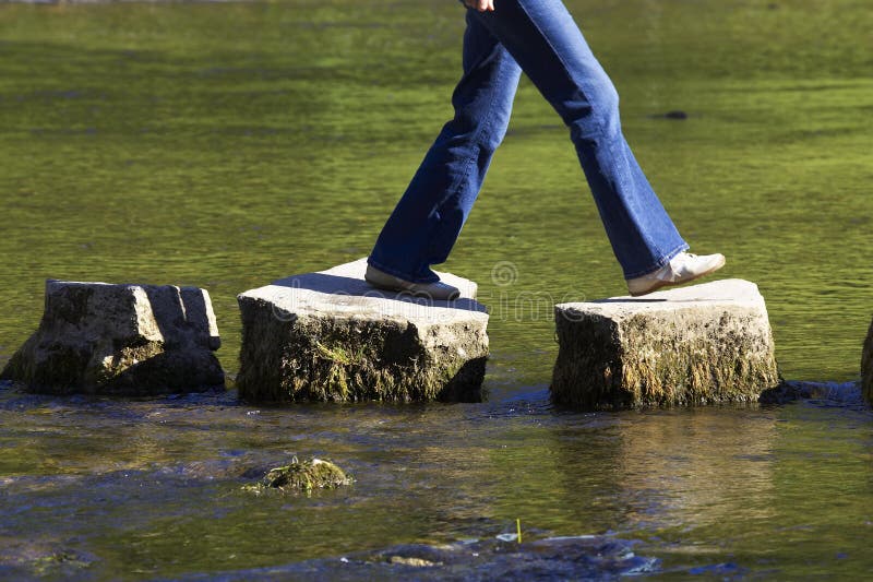 Überqueren drei stepping stones in einem Fluss weiblich.