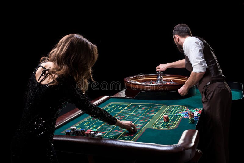 Croupier- och kvinnaspelare på en tabell i en kasino Bild av A.C. royaltyfri bild Croupier- och kvinnaspelare på en tabell i en kasino Bild av A.C. royaltyfri bild