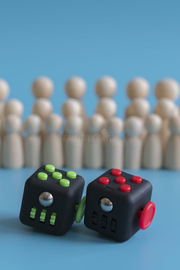 Crowd calm concept. answer how to calm the crowd. Cube stress reliever and wooden figures on a blue background. vertical photo stock photo Crowd calm concept. answer how to calm the crowd. Cube stress reliever and wooden figures on a blue background. vertical photo stock photo