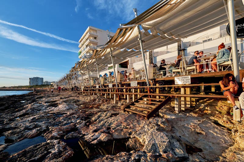 Ibiza Island, Spain - May 1, 2018: Crowds of people meet the sunset at the seafront terrace of Cafe Del Mar. This place is famous for views to the sunsets and lounge music. Ibiza, Balearic Islands. Spain. Ibiza Island, Spain - May 1, 2018: Crowds of people meet the sunset at the seafront terrace of Cafe Del Mar. This place is famous for views to the sunsets and lounge music. Ibiza, Balearic Islands. Spain