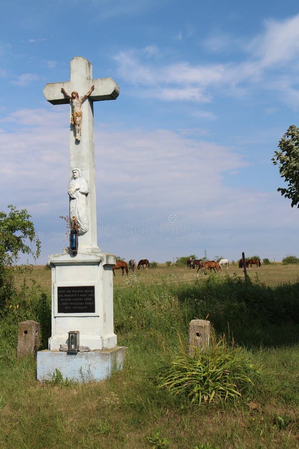 Crucifix in hayfield with horses near Devinska Nova Ves