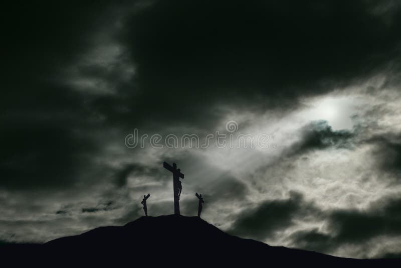 A depiction of the crucifixion of Jesus Christ on a cross with 2 other robbers nearby on Calvary. The sky is darkened and rays of light break through the clouds onto the cross for drama. Concept of the death of Jesus on Good Friday and His resurrection on Easter Sunday. Horizontal orientation with copy space. A depiction of the crucifixion of Jesus Christ on a cross with 2 other robbers nearby on Calvary. The sky is darkened and rays of light break through the clouds onto the cross for drama. Concept of the death of Jesus on Good Friday and His resurrection on Easter Sunday. Horizontal orientation with copy space.