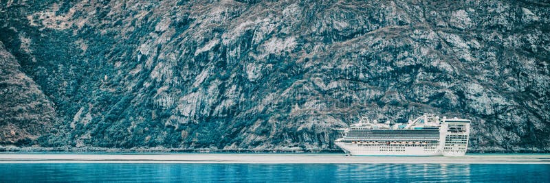 Cruise ship sailing at Glacier Bay, Alaska, on blue glacial ocean water and icebergs. Panoramic banner of Arctic travel background