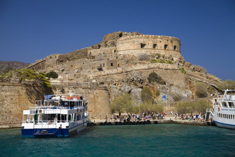 Cruise to the island of Spinalonga. Small boat on the blue lagoon. Spinalonga fortress on the island of Crete, Greece.