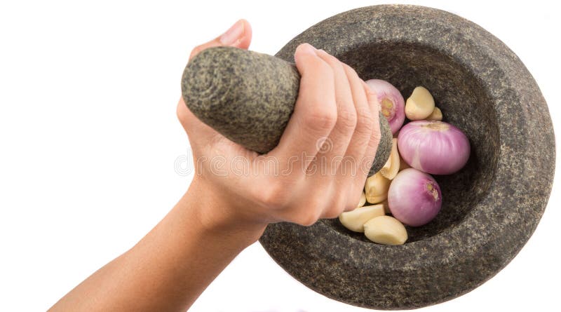 Female hand crunching onions and garlic stone mortar and pestle over white. Female hand crunching onions and garlic stone mortar and pestle over white