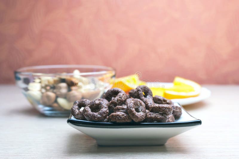 Crunchy Czekoladowi zboża Round owsy w naczyniu, Szklanym pucharze dokrętki i pomarańcze plasterkach w Białym talerzu na Drewnian obrazy royalty free Crunchy Czekoladowi zboża Round owsy w naczyniu, Szklanym pucharze dokrętki i pomarańcze plasterkach w Białym talerzu na Drewnian obrazy royalty free
