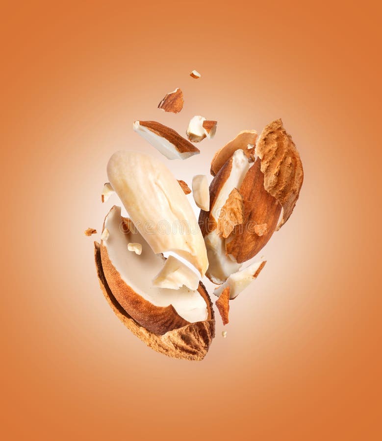 Crushed dried almonds with shell in air close up on brown background stock photos