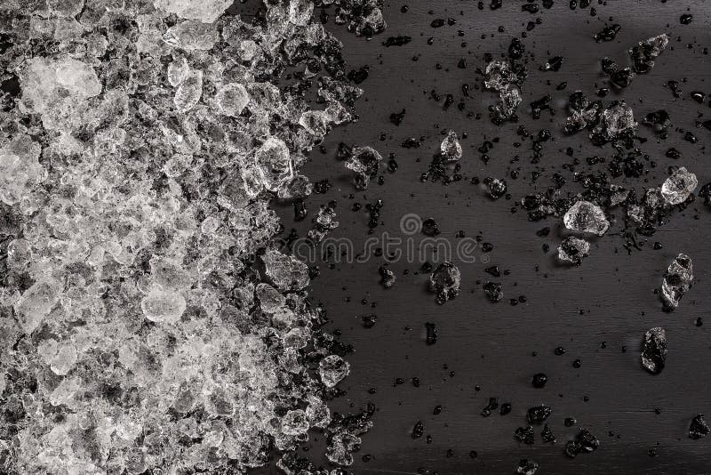 Crushed ice cubes on vintage black wooden table. Top view