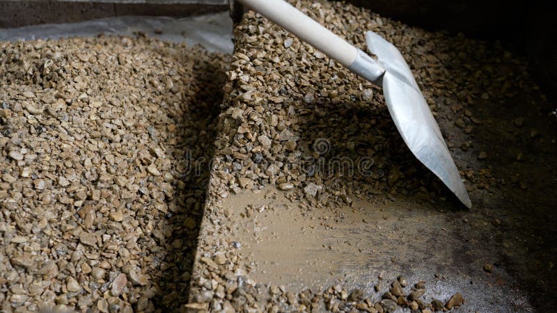 Crushed stone with a shovel, close-up. A pile of gray rubble with a shovel and small stones in the room. Crushed stone with a shovel, close-up. A pile of gray rubble with a shovel and small stones in the room.