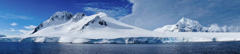 Cruzamento através do canal de Neumayer com as montanhas cobertos de neve na Antártica