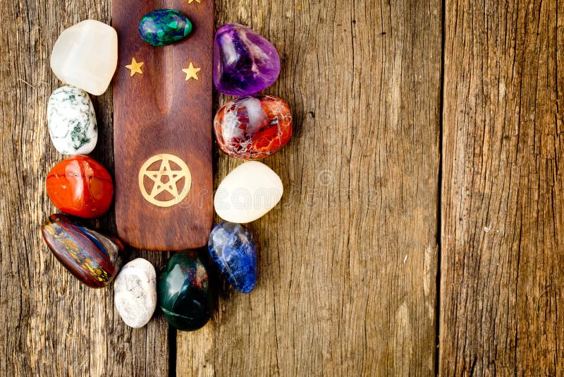 Colorful crystal stones around wood with brass pentagram symbol