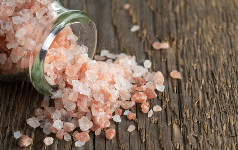 Crystals of Pink Himalayan Salt on a Rough Wooden Surface. Stock Photo