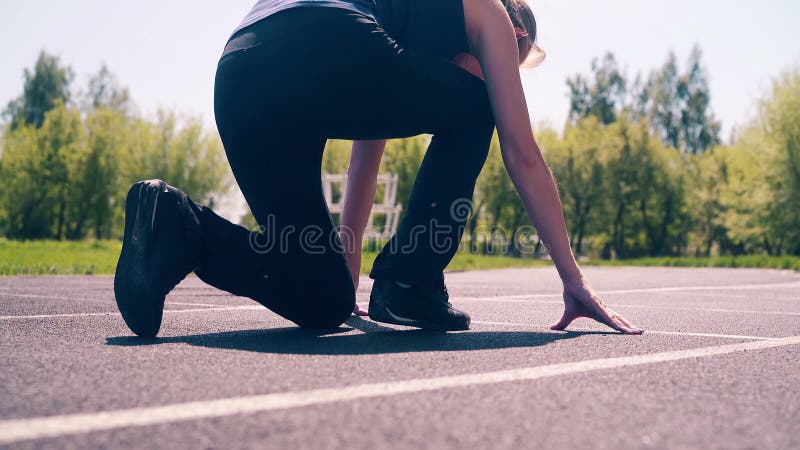 CU: Chica joven, constitución deportiva, en el estadio Ella va a la línea del comienzo