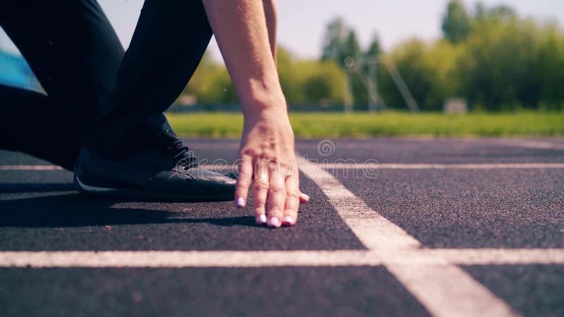 CU, vista lateral: Muchacha linda joven, constitución deportiva, en el estadio Ella va a la línea del comienzo