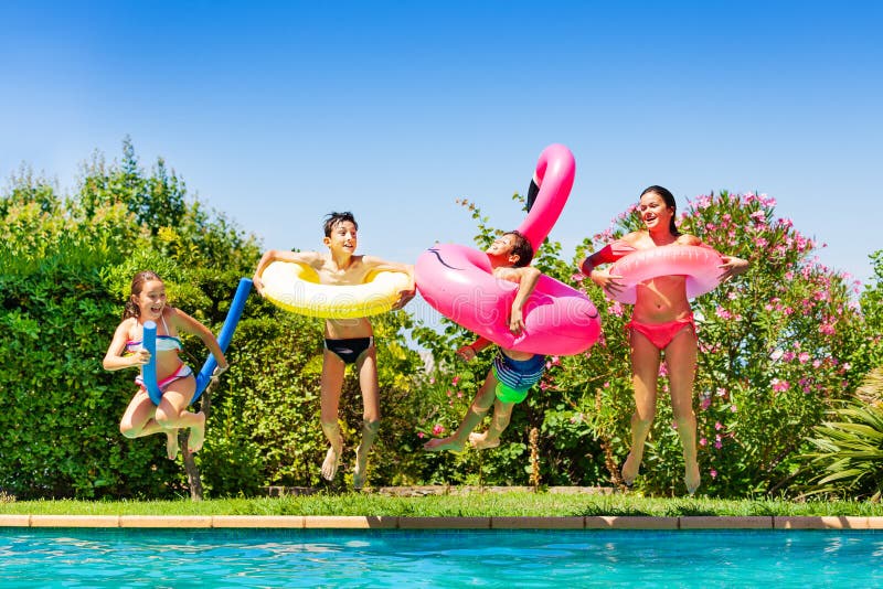 Cuatro amigos felices que saltan en la piscina foto de archivo libre de regalías Cuatro amigos felices que saltan en la piscina foto de archivo libre de regalías