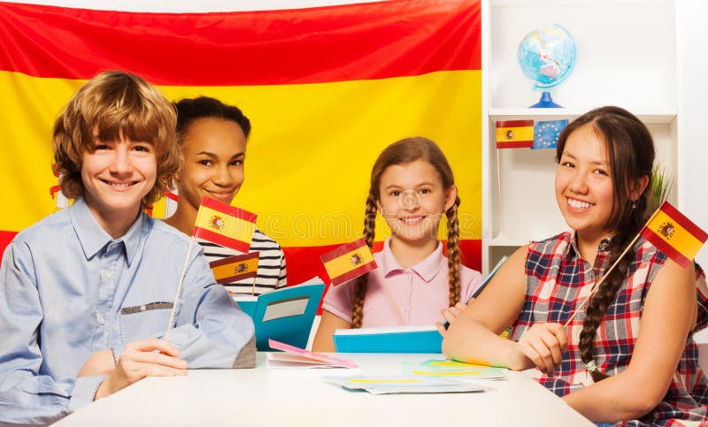 Cuatro estudiantes multiétnicos felices que sostienen banderas fotos de archivo libres de regalías Cuatro estudiantes multiétnicos felices que sostienen banderas fotos de archivo libres de regalías
