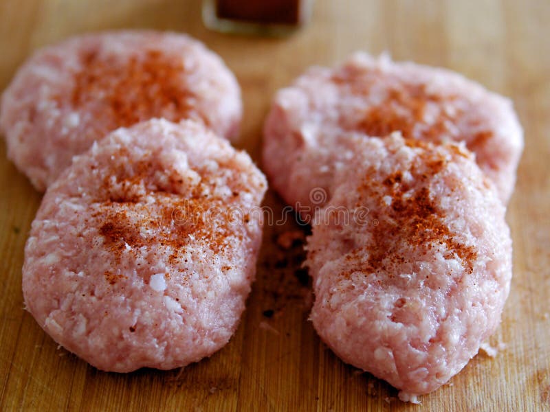 Cuatro hamburguesas crudas frescas del pavo en un tablero de madera, cubierto con el condimento imagenes de archivo Cuatro hamburguesas crudas frescas del pavo en un tablero de madera, cubierto con el condimento imagenes de archivo