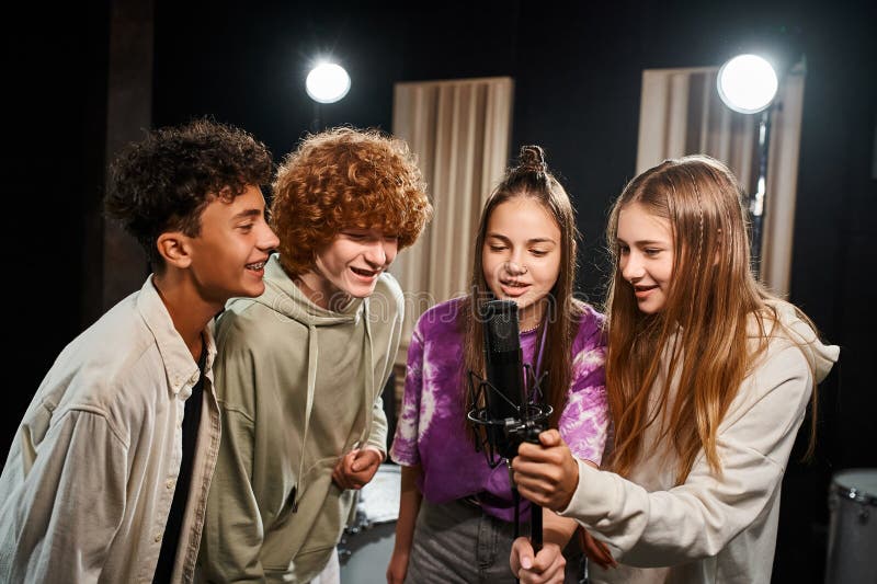 four joyous talented teenagers in casual outfits singing together while in studio, musical group, stock photo. four joyous talented teenagers in casual outfits singing together while in studio, musical group, stock photo