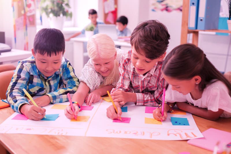 Cuatro niños que escriben junto en un périódico imagen de archivo libre de regalías Cuatro niños que escriben junto en un périódico imagen de archivo libre de regalías