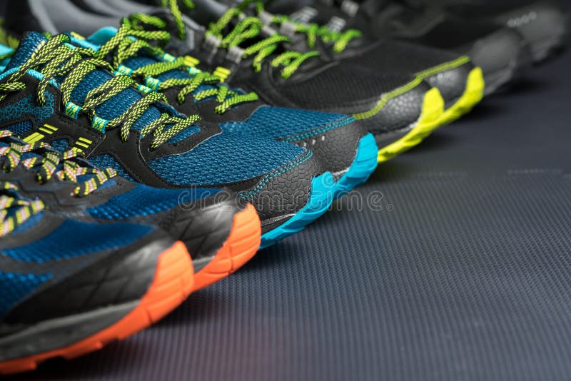 Four pairs of running shoes / exercise trainers lined up in a row on a gym floor with potential text / writing space. Four pairs of running shoes / exercise trainers lined up in a row on a gym floor with potential text / writing space.