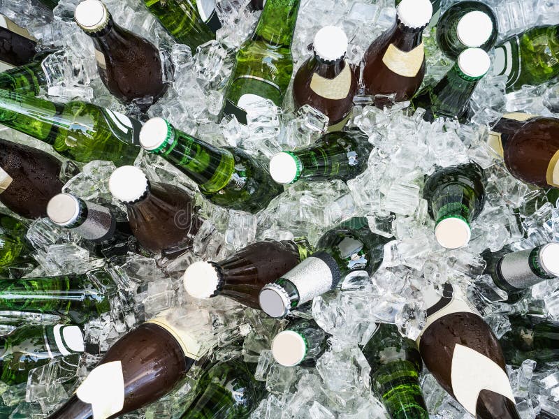 Cubes of ice and colorful bottles with cold beer