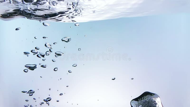Cubetti di ghiaccio che cadono spruzzata nell'acqua su fondo bianco, movimento lento del colpo, ora legale fresca della bevanda