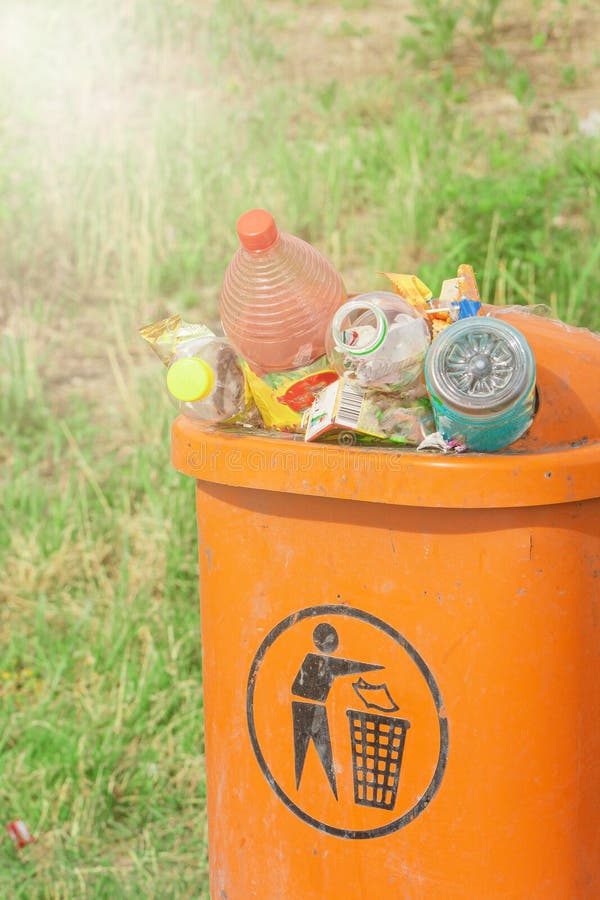 Cubo De Basura Naranja Rebosante De Botellas De Basura Y Papel En El Fondo De La Hierba Verde Esperando Ser Enviados Imagen de archivo Imagen de bolso contra 272985391