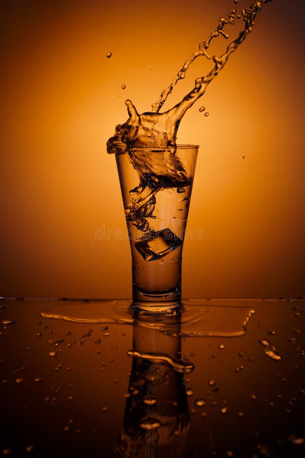 Cubos de gelo que espirram no vidro da água imagens de stock royalty free Cubos de gelo que espirram no vidro da água imagens de stock royalty free