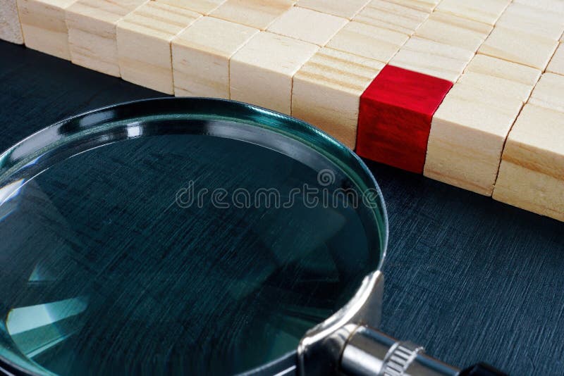 Wooden cubes and one red next to magnifying glass. Talent acquisition concept. Wooden cubes and one red next to magnifying glass. Talent acquisition concept.