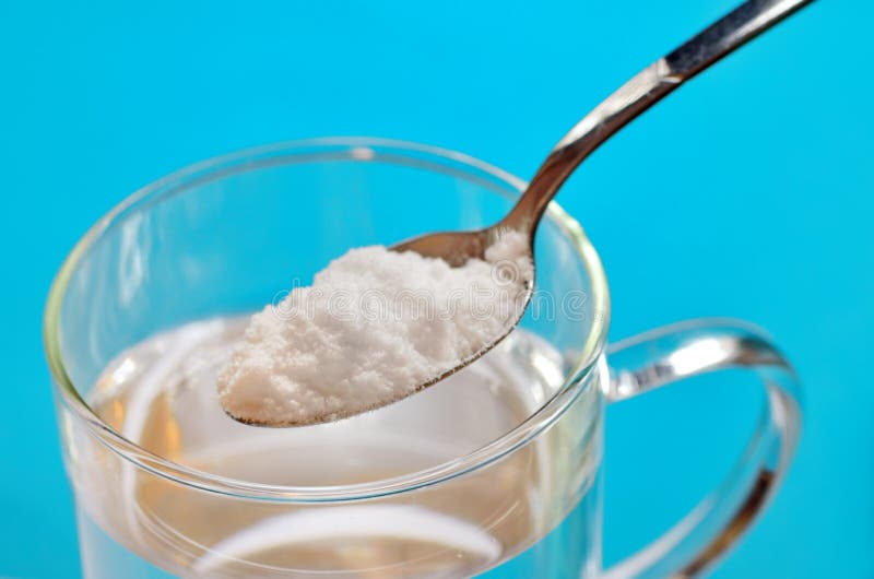 Cucchiaio del bicarbonato di sodio sopra bicchiere d'acqua immagini stock Cucchiaio del bicarbonato di sodio sopra bicchiere d'acqua immagini stock