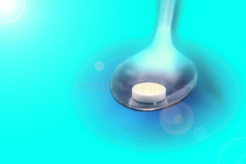 Cucchiaio del metallo con le pillole bianche su fondo blu, concetto paziente di trattamento immagini stock Cucchiaio del metallo con le pillole bianche su fondo blu, concetto paziente di trattamento immagini stock
