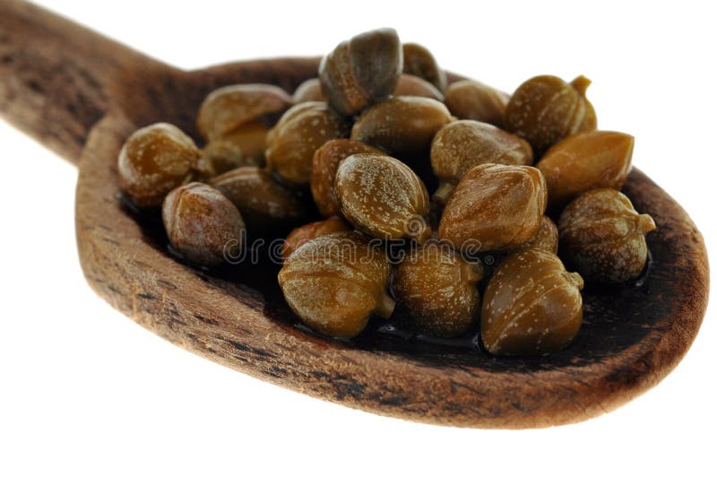 Cucchiaio di legno dei capperi su un fondo bianco fotografia stock libera da diritti Cucchiaio di legno dei capperi su un fondo bianco fotografia stock libera da diritti