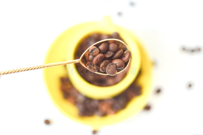 Cuchara del vintage con los granos marrones del café en el fondo una taza amarilla Granos de caf? con la cuchara fotografía de archivo Cuchara del vintage con los granos marrones del café en el fondo una taza amarilla Granos de caf? con la cuchara fotografía de archivo