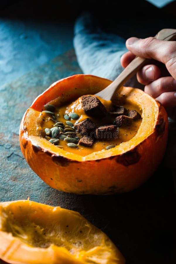 Cucharee a disposición con la sopa de la calabaza y la calabaza con las semillas de girasol y los cuscurrones fotografía de archivo Cucharee a disposición con la sopa de la calabaza y la calabaza con las semillas de girasol y los cuscurrones fotografía de archivo