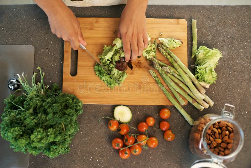 Cuchillo de mano y superior para verduras en cocina con espárragos de corte y cocina con nutrición para la cena. 2. º cocinera fotos de archivo