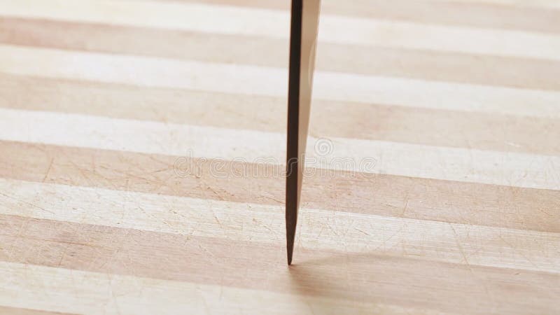 Cuchillo oscuro del cuchillo de cocina, tiro cerrado Punto de cintura girando sobre una mesa de madera Antecedentes abstractos En almacen de video